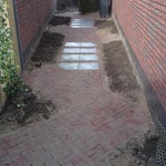 Doorloop tussen de gevels van gebakken Dikformaat Ruston rood met leisteentegels Mustang 40x40. -Hoveniersbedrijf C.K. van Mourik-